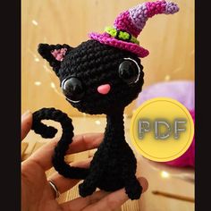 a crocheted black cat with a pink hat on it's head is shown