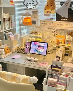 a desk with a computer monitor on top of it next to a teddy bear hanging from the ceiling