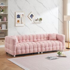 a pink couch sitting on top of a hard wood floor next to a white rug