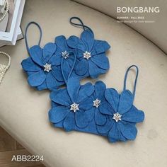 three blue flowers are sitting on the back of a white couch next to pearls and beads