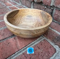 a wooden bowl sitting on top of a brick floor