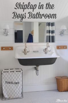 a bathroom sink sitting under a mirror next to a towel dispenser and basket