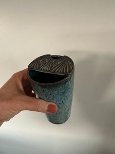 a hand is holding a cup that has been placed on the wall