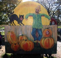 a man standing in front of a sign with pumpkins and cats painted on it