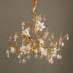 a chandelier with white flowers hanging from it's sides and crystal drops