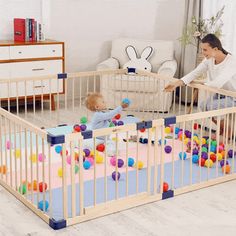 a woman playing with her baby in a crib filled with colorful balls and toys