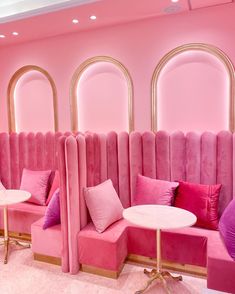 pink couches and tables in a room with arched windows, gold trim around them