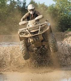 a man riding on the back of an atv through mud