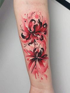 a red and black flower tattoo on the left arm with watercolor splashes around it