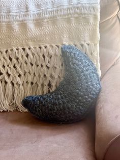 a crocheted pillow sitting on top of a couch next to a white blanket