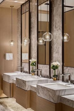 a bathroom with marble counter tops and two sinks in front of three mirrors on the wall