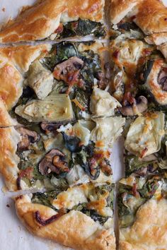 a pizza with mushrooms, spinach and cheese is cut into eight pieces to be eaten