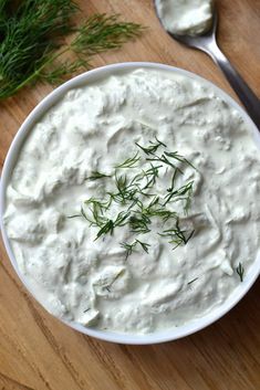 a white bowl filled with sour cream and topped with fresh dill sprigs