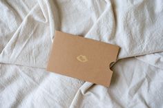 an open cardboard box sitting on top of a white bed sheet covered in linens