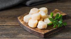 cubes of diced potatoes on a wooden cutting board with green sprigs