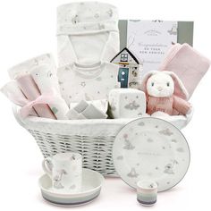 a white basket filled with baby items on top of a table next to a cup and saucer