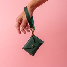 a person's hand holding a small green purse with a gold clasp on it