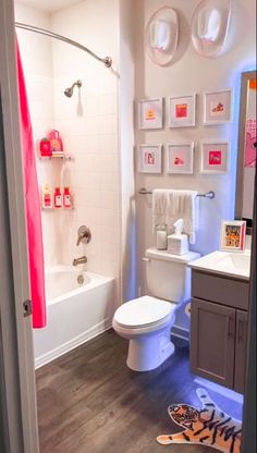 a bathroom with pictures on the wall, toilet and bathtub