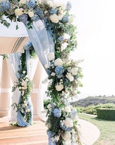 a blue and white wedding arch decorated with flowers