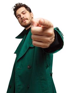 a man in a green coat pointing at the camera with his finger up and wearing a black jacket