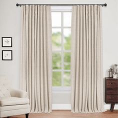 a white chair sitting in front of a window with curtains hanging on the windowsill