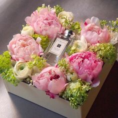 an arrangement of flowers in a box with a perfume bottle on the top and bottom