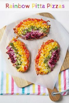 rainbow pita pizzas on a cutting board with a fork and napkin next to them