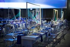 the tables are set up for an event with blue linens and clear glassware