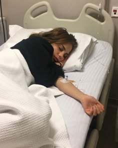 a woman laying in a hospital bed with her hand on the side of the bed