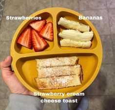 a person holding a yellow plate with different types of food on it, including strawberries, bananas and cream cheese toast