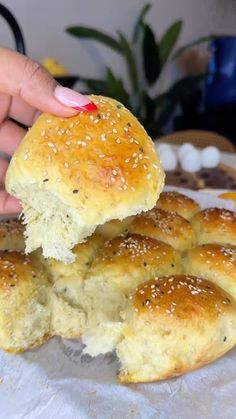 a person is picking up some bread from a plate with other rolls in the background