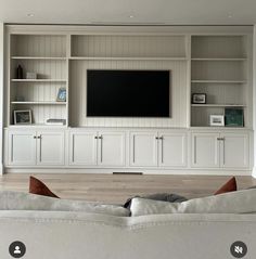 a living room with white furniture and a flat screen tv mounted on the wall above it