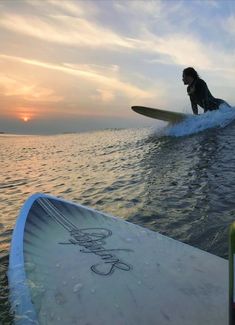 a person riding a surfboard on top of a wave in the ocean at sunset