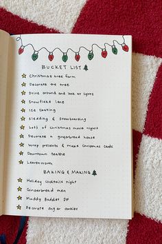 an open christmas list book sitting on top of a red and white blanket