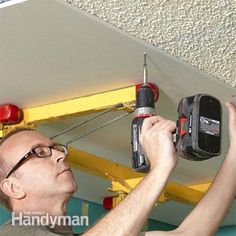 a man holding a driller and an electric tool in his hand while working on a ceiling