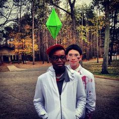 two young men standing next to each other in front of trees and a green kite