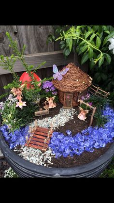 a potted planter filled with lots of flowers and small fairy houses on top of it