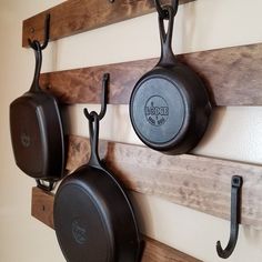 pots and pans are hanging on the wall next to hooks that hang from wooden planks