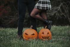 two people standing next to each other holding pumpkins