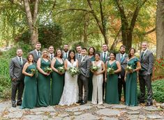 a group of people standing next to each other in front of trees and leaves on the ground