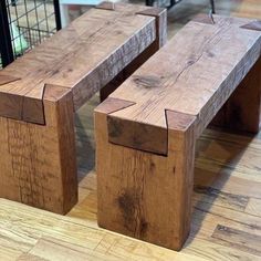 two wooden benches sitting on top of a hard wood floor next to a wire cage