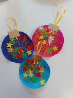 three paper plates with stars on them and tags hanging from the top one is blue, pink, yellow and green