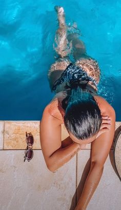 a woman is sitting in the pool looking down at her feet