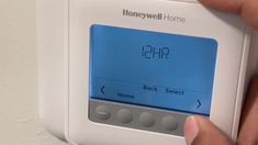 a person is pressing the button on a honeywell home program