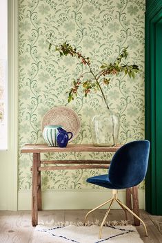 a blue chair sitting in front of a table with a vase on top of it