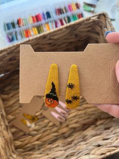 a pair of corn earrings is shown in front of a basket with crayons