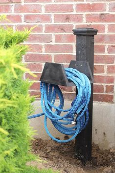 a blue rope is attached to a black post in front of a red brick wall