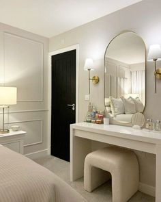 a bedroom with a vanity, mirror and stool next to a bed in the room