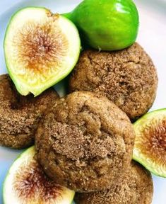 some cookies are sitting on a plate with figs and an apple in the background