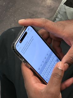 a person holding a cell phone in their left hand and typing on the keyboard with both hands